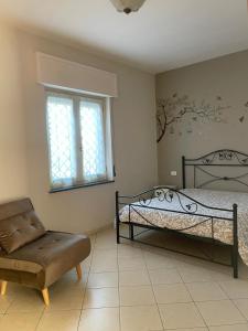 a bedroom with a bed and a chair and a window at Villa Aura in Torre del Greco