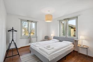 a white bedroom with a bed and two windows at Altwiesenstrasse 144 in Zurich