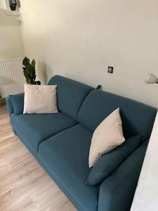 a blue couch with two pillows in a living room at Charmante maisonnette cosy près de Paris in Deuil-la-Barre