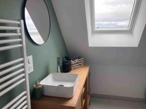 uma casa de banho com um lavatório branco e um espelho. em Jolie maison binicaise em Gicquel