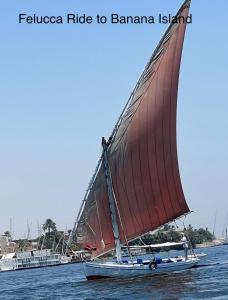 a boat with a red sail in the water at Full Moon House in Luxor