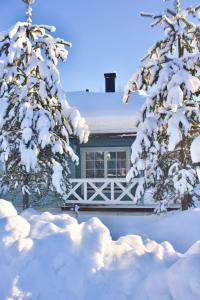 una casa cubierta de nieve frente a dos árboles en Kolazko Apartments, en Vuokatti