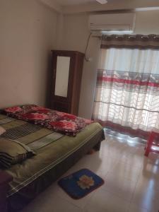 a bedroom with a bed and a window and a rug at Secured Family Studio Apartment-near Airport,AC,Fridge,WiFi,Stove in Dhaka