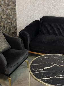 Sala de estar con sofá negro y mesa de centro en Aparan Hotel, en Aparan