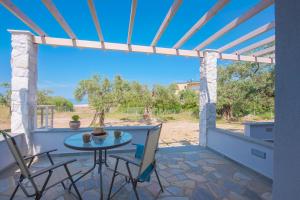 un patio con tavolo, sedie e vista sulla spiaggia di Terra di Olive Thassos a Potos