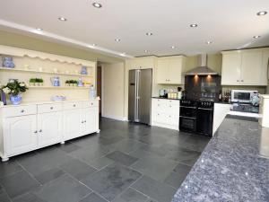 una grande cucina con armadietti bianchi ed elettrodomestici neri di 5 Bed in Conwy 48169 a Eglwys-Fâch