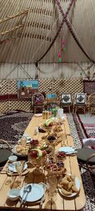 una mesa larga con platos de comida. en KARAKALPAK ETNO VILLAGE en Nukus