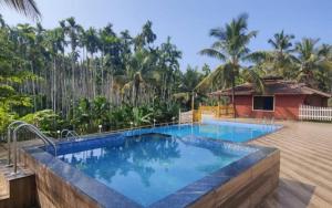 a swimming pool in front of a house with trees at Pepper Paradise by StayApart in Dandeli