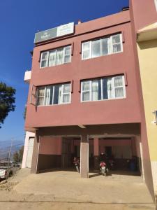 a pink building with a garage in front of it at Hotel Mansarovar in Dailekh