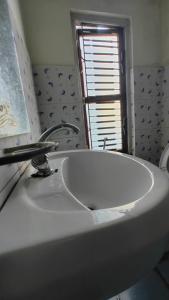 lavabo blanco en un baño con ventana en Hotel Mansarovar, en Dailekh