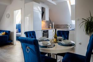 a kitchen and dining room with a table and blue chairs at Love House Balatonboglár Apartman in Balatonboglár
