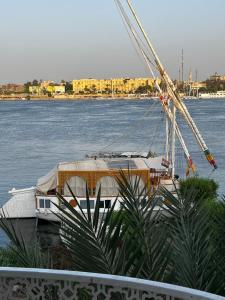 una barca è ormeggiata in acqua accanto di Full Moon House a Luxor