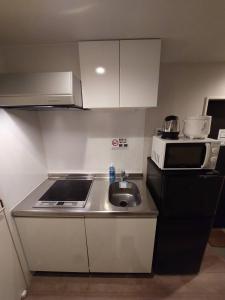 eine kleine Küche mit Spüle und Mikrowelle in der Unterkunft Comfort CUBE PHOENIX Yakuin in Susakiuramachi + 6 Fotos