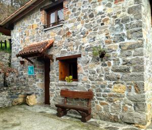 un banco sentado fuera de un edificio de piedra en Casa Rural El Cotu en Cangas de Onís, en Cangas de Onís