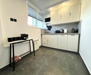 a kitchen with white cabinets and a concrete floor at Apartment Amber Liepaja in Liepāja