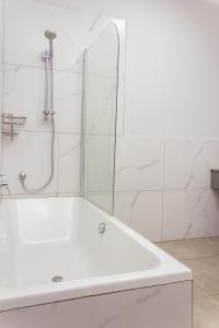a white bath tub in a bathroom with white tiles at Cherrywood Estate Apartment in Blantyre