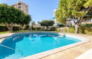 a large blue swimming pool with trees and buildings at Apartamento Huellas en la Arena in El Campello