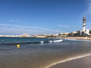 una playa con una bola amarilla en el agua y un faro en CASA SALMÓN en Cádiz