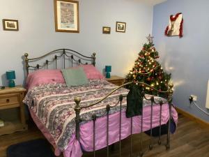 Charming 1-Bed Apartment in Scarning Near Dereham في ديرهام الشرقيه: غرفة نوم مع شجرة عيد الميلاد وسرير