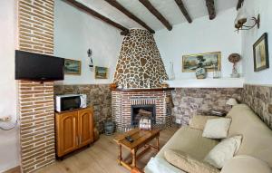 sala de estar con chimenea, sofá y TV en Cozy Home In Benalaureia With Kitchen, en Benalauría