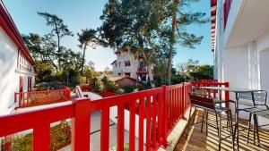 a red fence on a porch with a table and chairs at Haut Saint Georges - Un emplacement exceptionnel au centre-ville et au calme à quelques pas du lac marin in Soorts-Hossegor