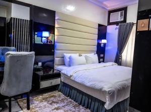 a bedroom with a bed and a desk and a chair at CHILLERS HOTEL AND SUITES in Aiyetoto-Asogun