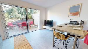 a living room with a table and chairs and a patio at TERRASSES SAINT GEORGES - Un emplacement exceptionnel au centre-ville et au calme à quelques pas du lac marin in Soorts-Hossegor