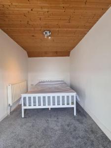 a white bed in a room with a wooden ceiling at Bron Haul, Mountain Views in Brynteg