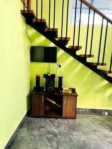 Habitación con escritorio, TV y escaleras. en Nandhanam Homestay, en Palakkad