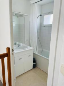 La salle de bains blanche est pourvue d'un lavabo et d'une douche. dans l'établissement Maison cosy, bien équipée, 15 min Futuroscope, CHU, à Poitiers