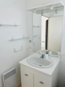 Baño blanco con lavabo y espejo en Maison cosy, bien équipée, 15 min Futuroscope, CHU en Poitiers