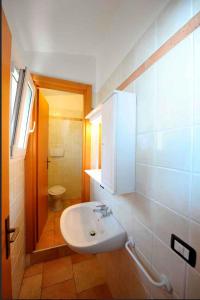 ein Badezimmer mit einem weißen Waschbecken und einem WC in der Unterkunft Apartments in Peschiera del Garda 22099 in Peschiera del Garda