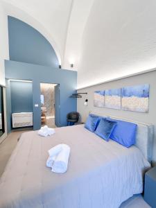 een slaapkamer met een groot wit bed met blauwe kussens bij Dimora Minelli Suites in Monopoli