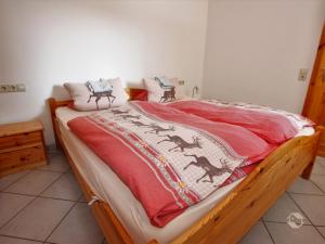 a bed with a red blanket on top of it at Ferienwohnung Linder in Schömberg