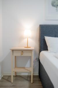 a bedside table with a lamp on it next to a bed at Casa Romana Apartmanok Siófok By BLTN in Siófok