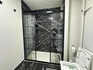 La salle de bains est pourvue d'une douche en marbre noir et d'un lavabo. dans l'établissement APARTİST 2, à Istanbul