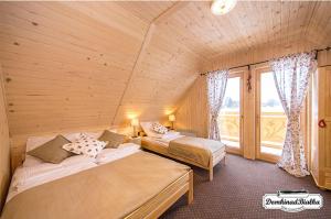 a bedroom with two beds and a large window at Domki nad Białką in Czarna Góra