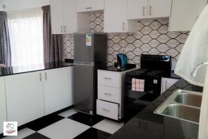 a kitchen with a black refrigerator and a black and white floor at Likulezi Apartment 1 in Blantyre