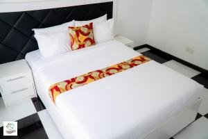 a bedroom with a white bed with a red pillow at Likulezi Apartment 1 in Blantyre