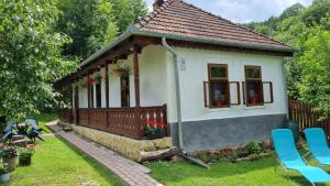 una pequeña casa con una valla y flores en el patio en Hutai Meseház, en Háromhuta