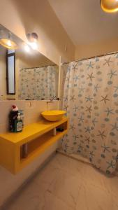a bathroom with a yellow sink and a shower curtain at Jamiitown Homes in Kilifi