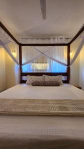 a bedroom with a large white bed with a window at Jamiitown Homes in Kilifi