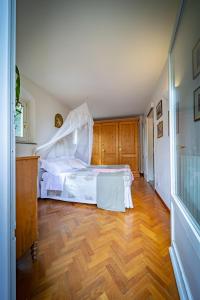 1 dormitorio con 1 cama con sábanas blancas y suelo de madera en Borgo Spedaletto 3 - Dolcevita Holiday, en Grassina