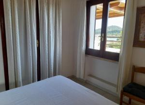 a bedroom with a bed and a window with a view at Villa Porto Giunco in Notteri
