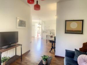 uma sala de estar com uma televisão de ecrã plano e um sofá em Pertini House em Arenzano