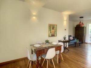 uma sala de jantar com uma mesa de madeira e cadeiras brancas em Pertini House em Arenzano