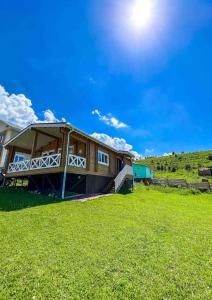 dom na trawiastym polu ze słońcem na niebie w obiekcie Домик в горах w mieście Besqaynar
