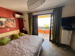 a bedroom with a bed and a television and a balcony at Athens Voula garden bungalow in Athens