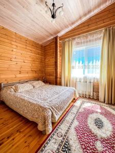 1 dormitorio con cama, ventana y alfombra en Домик в горах en Besqaynar