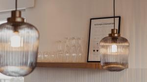 two glass pendant lights on a shelf with wine glasses at Urban Suite - Detmold in Detmold